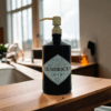 Hendrick's gin soap dispenser with vintage gold finish positioned on a wooden work surface next to a sink in a kitchen