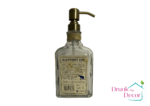 The Elephant dispenser is clear and rectangular with a navy and cream label. It has a jungle vibe with a rope and anchor tied around its neck. The pump is vintage bronze. The photo is of the back of the bottle.